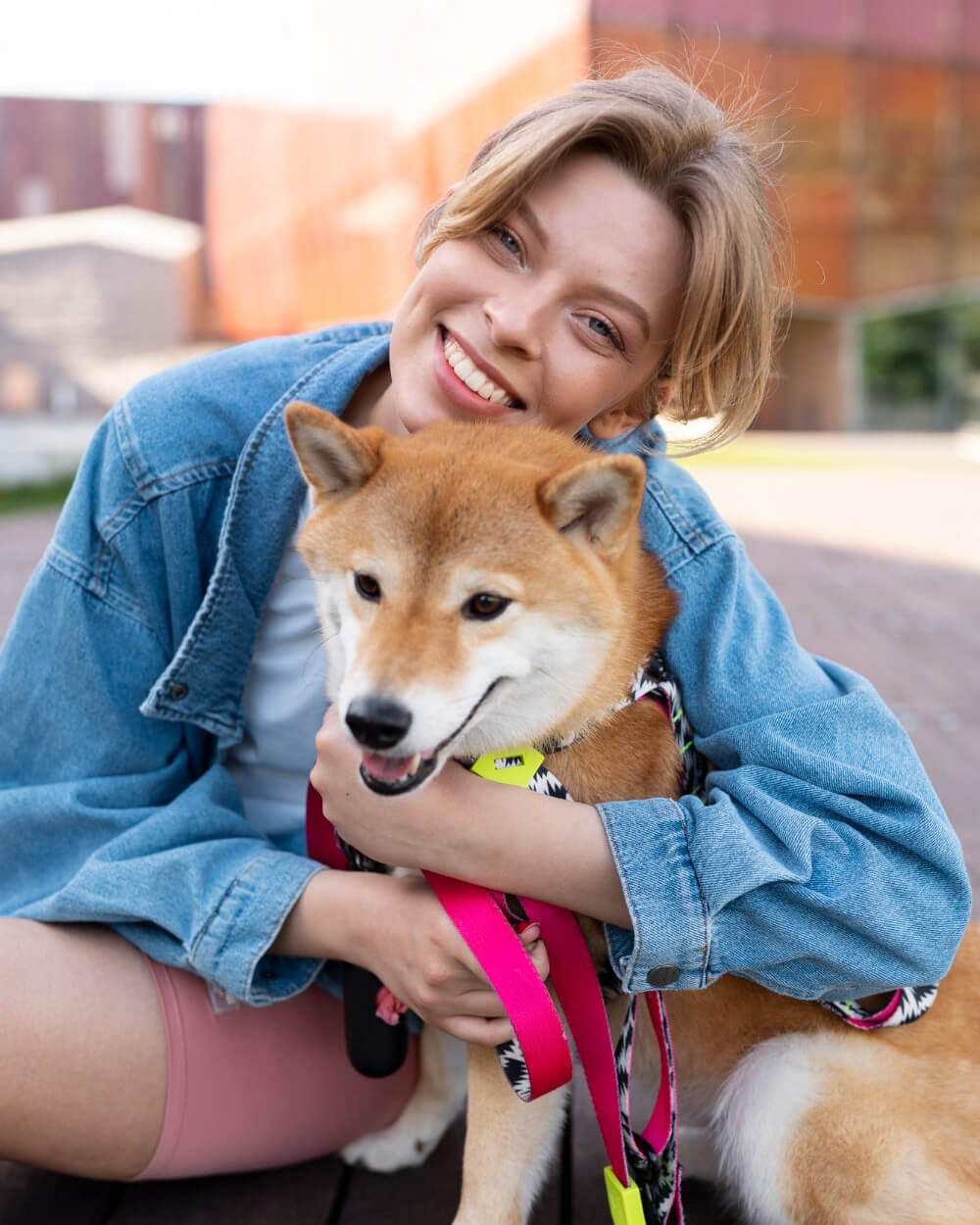 Woman holding a Shiba Inu dog outdoors with a blurred background